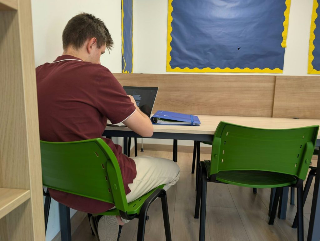Alumno de Dallington College estudiando con su portátil y su carpeta en una sala de estudio