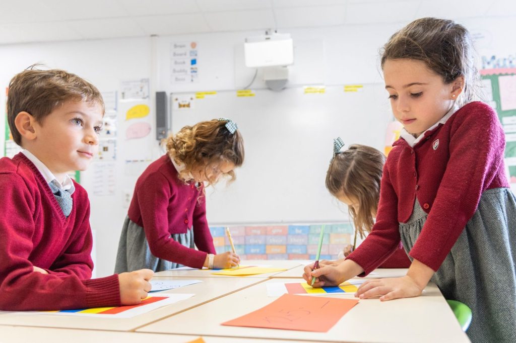 Alumnos de Primary escribiendo en las mesas de clase en Dallington School