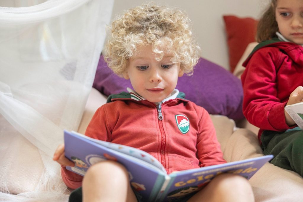 Niño pequeño leyendo un libro en inglés sentado sobre un cojín en Dallington School, colegio bilingüe en Madrid