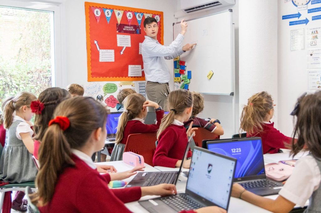 Profesor explicando en la pizarra a un grupo de alumnos de Primary con portátiles en Dallington School